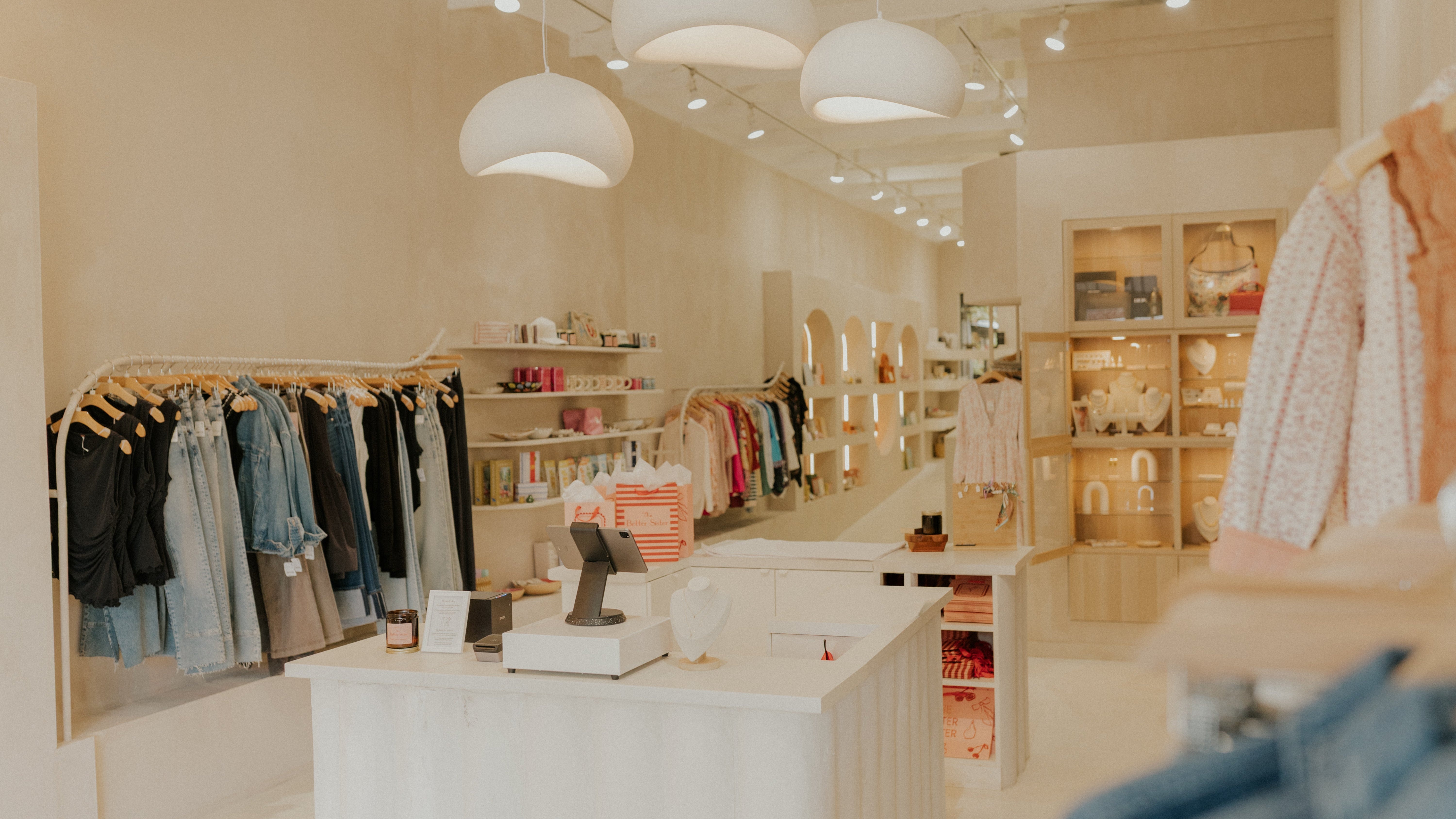 Interior of a clothing store with racks of clothes and a counter.